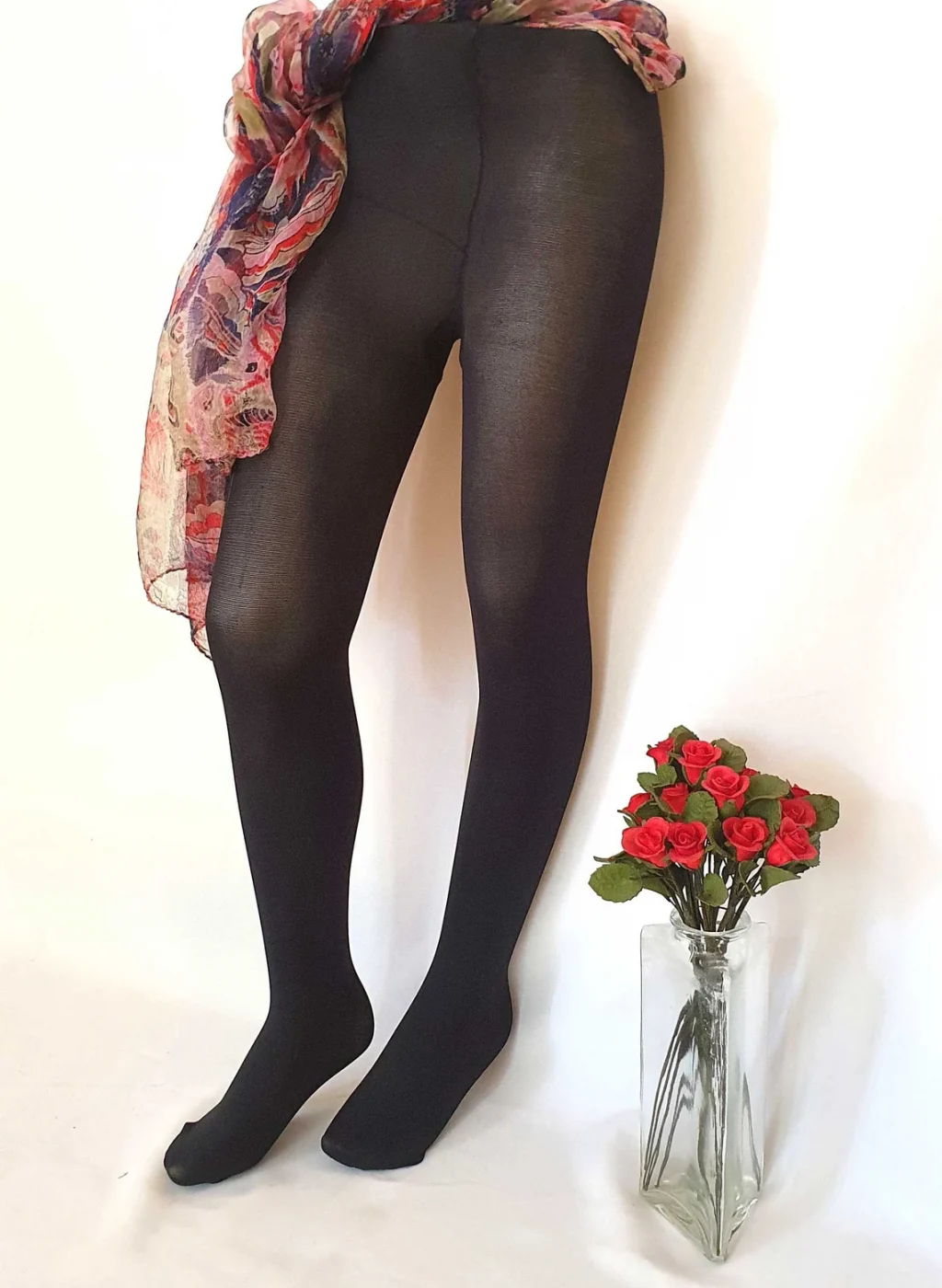 Pantimedias negras opacas con piernas de espaldas junto a un jarrón de rosas | Black opaque tights with back view legs beside a vase of roses