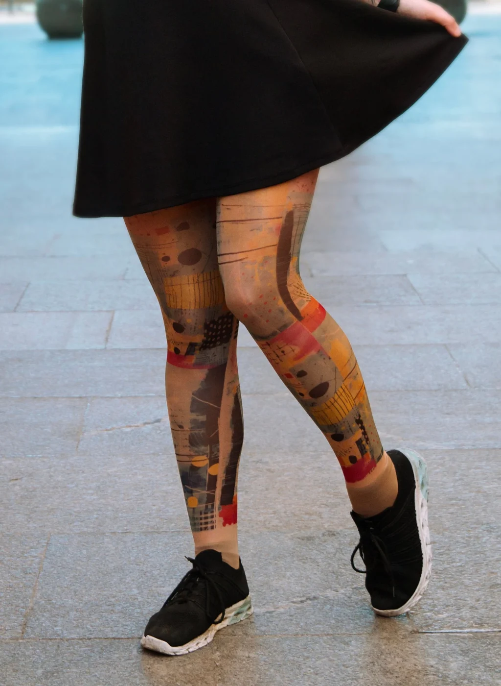 Piernas con pantimedias de arte abstracto moviéndose con falda negra en ambiente urbano | Legs wearing abstract art tights in motion with black skirt in urban area