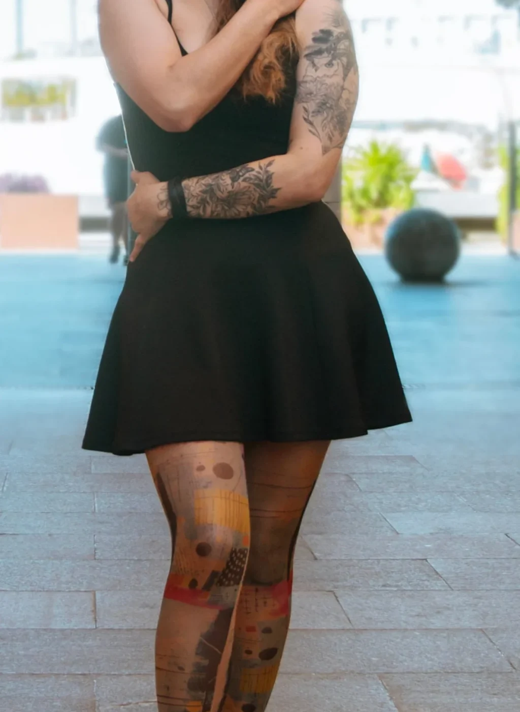 Mujer con pantimedias de arte abstracto posando con brazos cruzados y vestido negro | Woman wearing abstract art tights posing with crossed arms and black dress