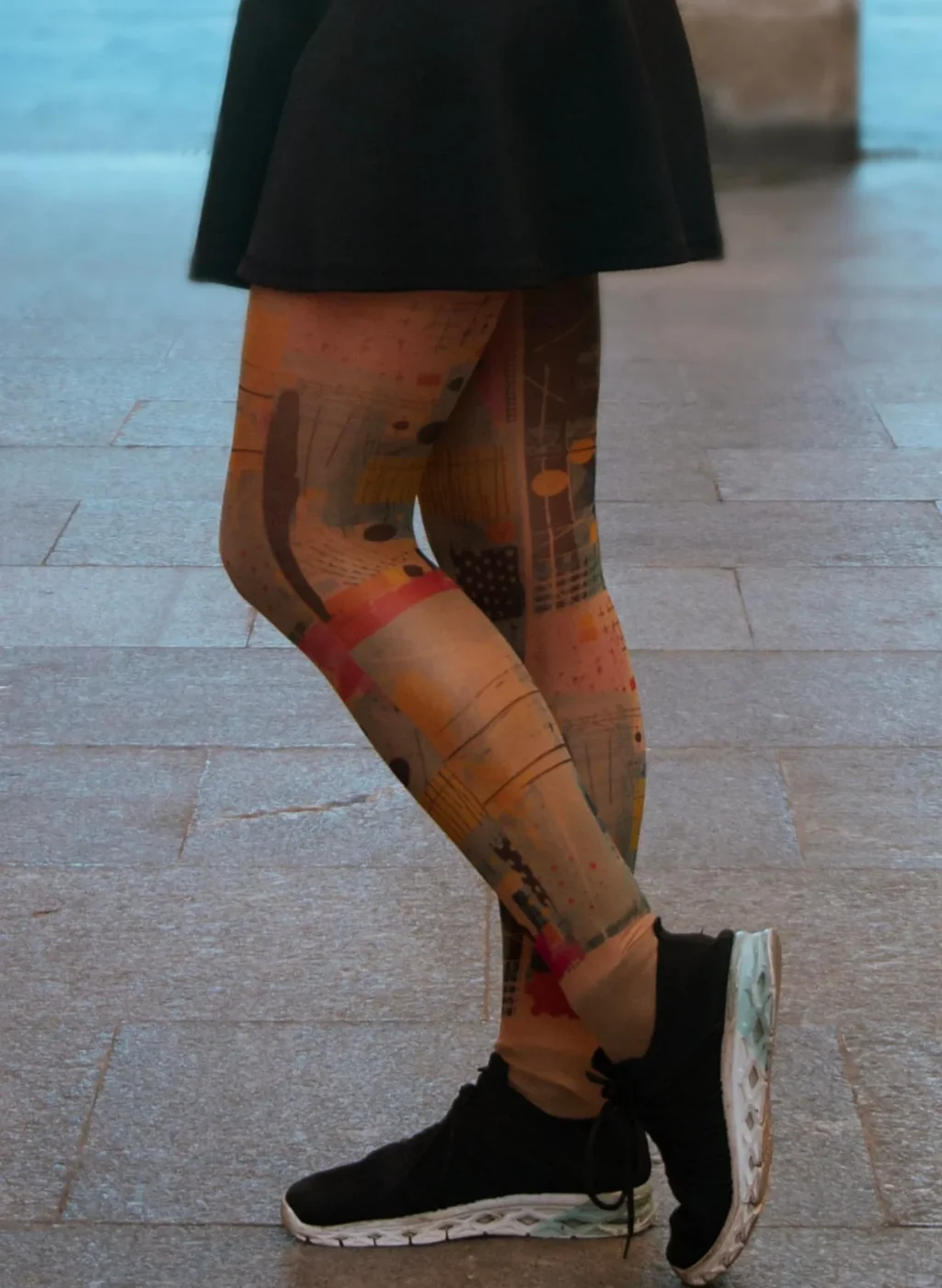 Piernas con pantimedias de arte abstracto en tonos naranjas y rojos caminando con falda negra | Legs wearing orange-red abstract art tights walking with black skirt