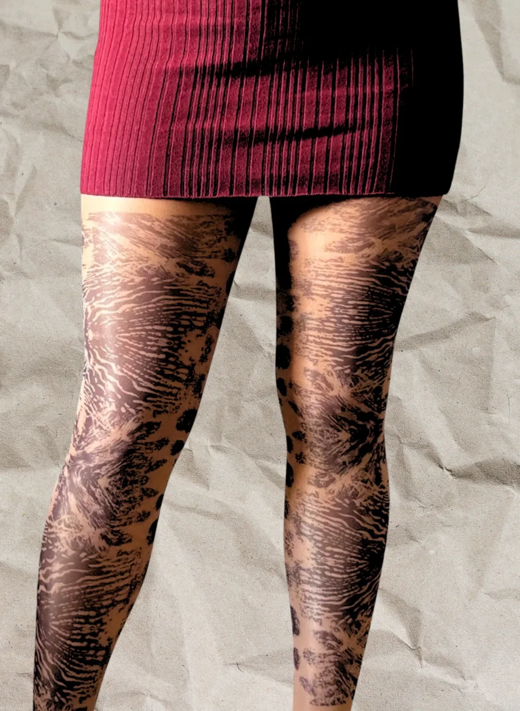 Piernas con pantimedias Wildwood en estampado negro rebajado sobre media transparente con falda burdeos y fondo beige arrugado | Legs wearing Wildwood tights with muted black pattern on sheer hosiery with burgundy skirt and wrinkled beige background
