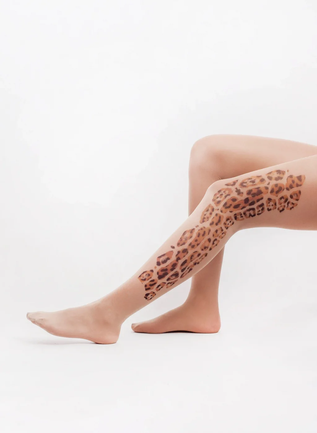 Sheer nude tattoo tights with full-leg tiger and leopard print pattern, studio white background | Pantimedias nude semitransparentes con estampado tatuaje de tigre y leopardo en toda la pierna, fondo blanco de estudio