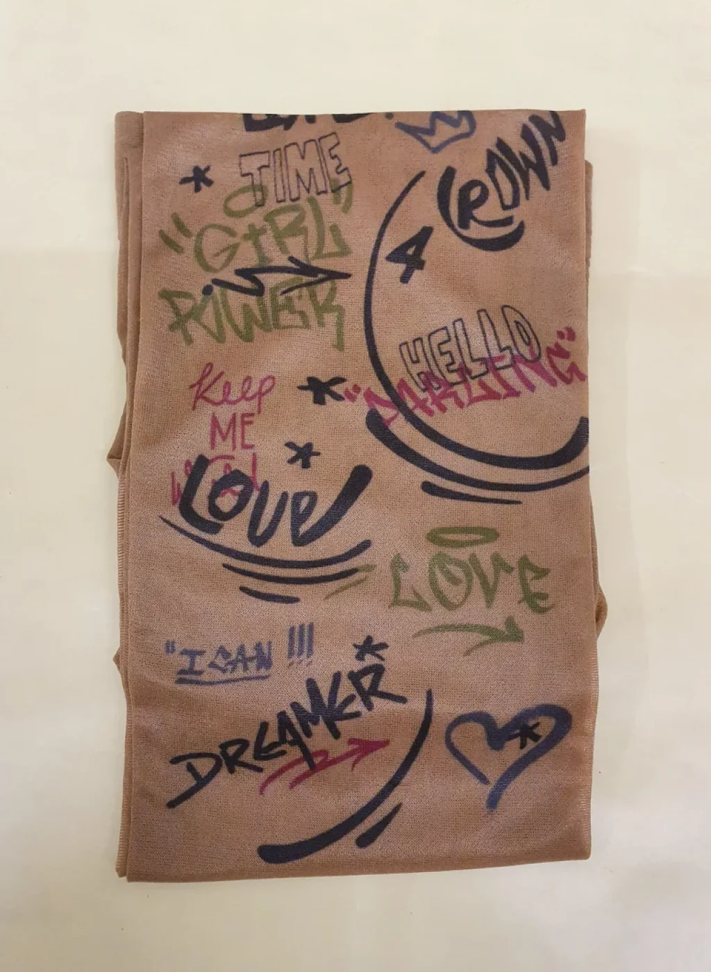 Folded semi-transparent pantyhose with colorful street-style graffiti words and doodle designs on a light background | Pantimedias semitransparentes dobladas con palabras y dibujos tipo grafiti de estilo urbano sobre fondo claro
