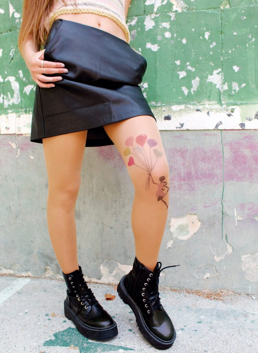 Sheer beige tattoo tights with girl holding colorful balloons design, worn with black skirt and boots | Pantimedias beige semitransparentes con diseño de niña con globos de colores, combinadas con falda negra y botas