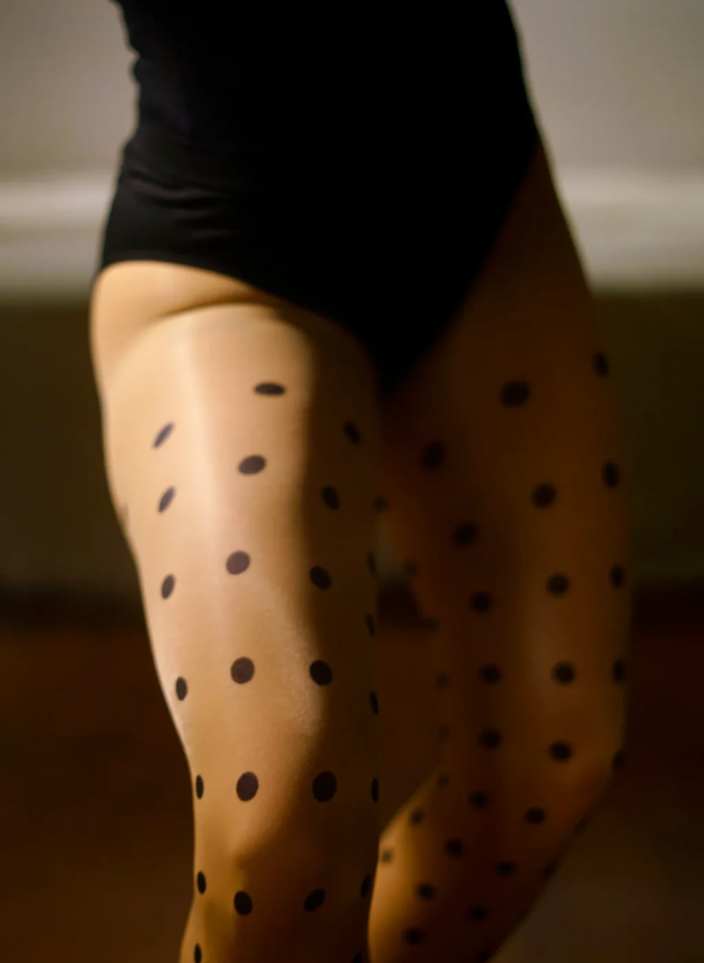 Sheer black polka dot tights close-up on upper leg, smooth and elegant fit | Pantimedias negras transparentes con lunares, detalle de muslo y ajuste elegante