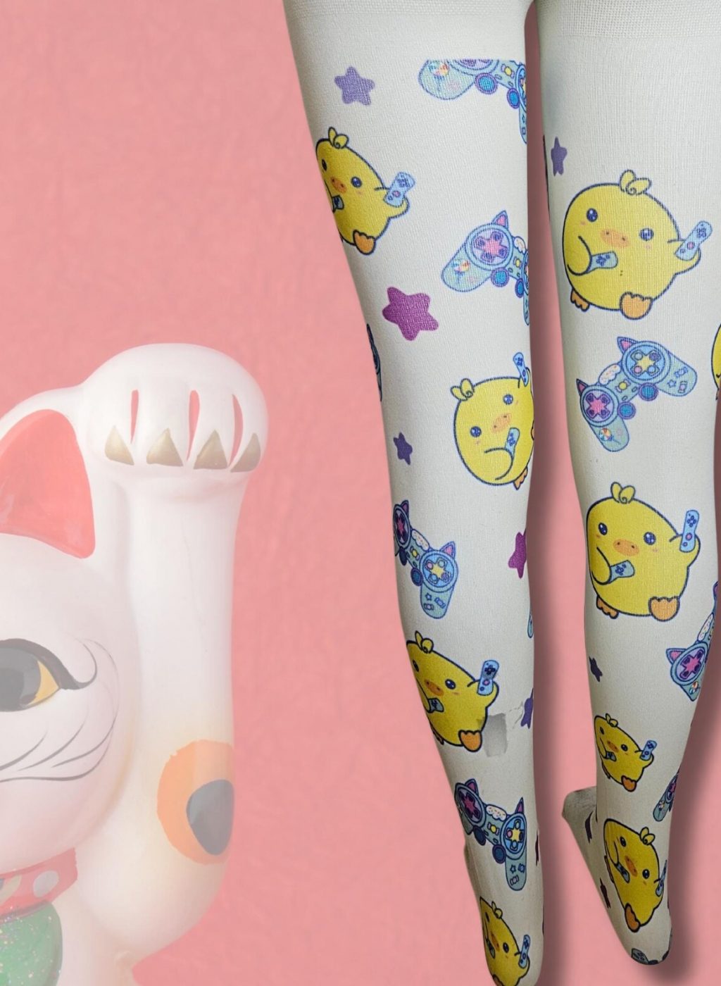 Medias infantiles blancas con dibujos kawaii de animales y estrellas, piernas juntas con fondo rosa y figura de gato de la suerte. White kids tights with kawaii animal and star designs, legs together on a pink background next to a lucky cat figure.