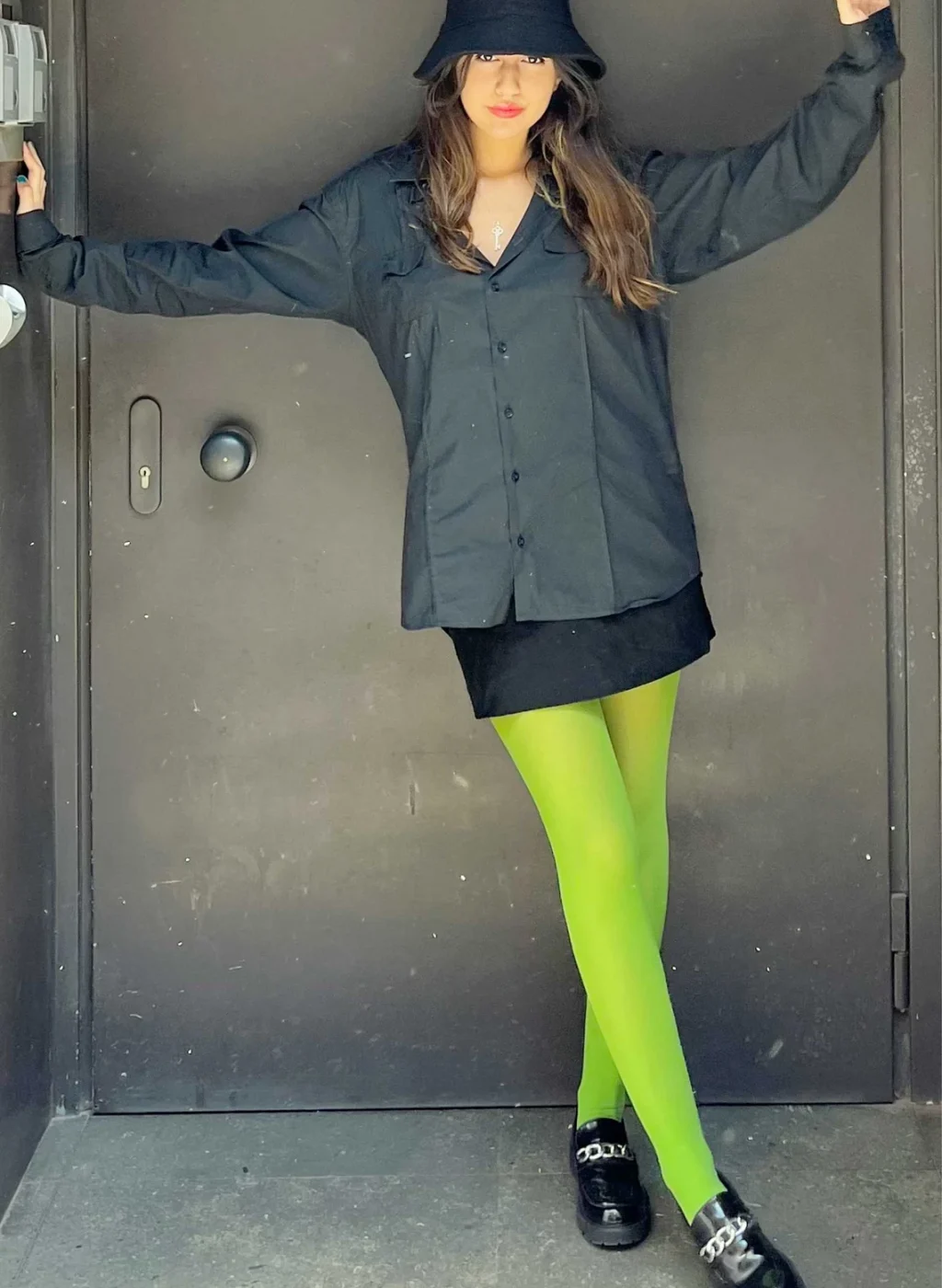 Mujer posando con pantimedias verde manzana frente a una puerta gris | Woman posing with apple-green tights in front of a grey door