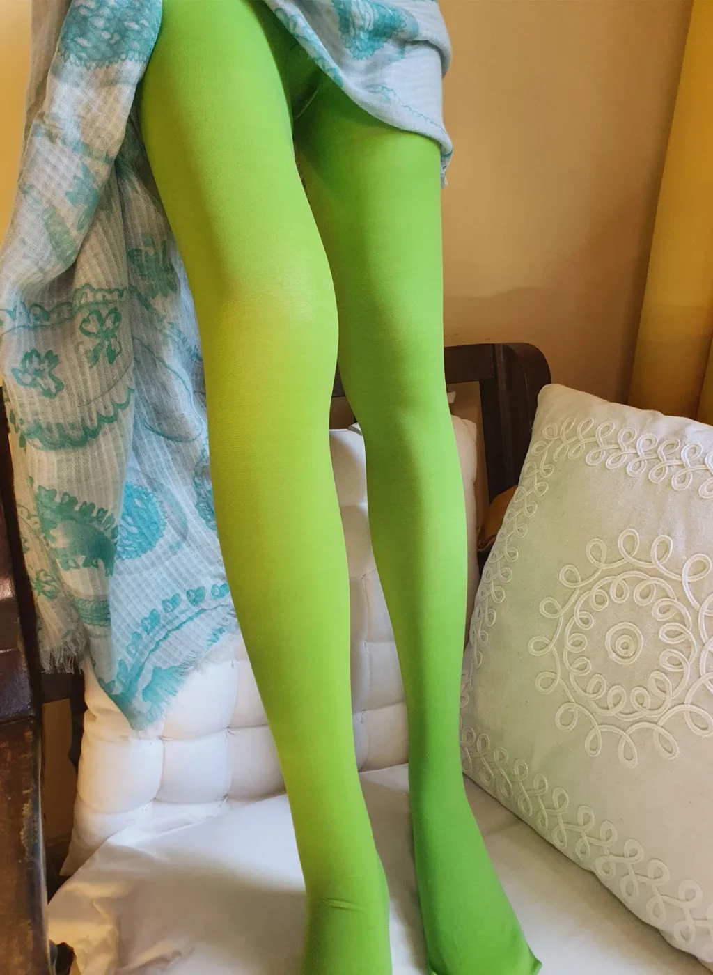 Pantimedias verde manzana en piernas estiradas apoyadas en silla, interior con manta azul | Apple green tights on stretched legs on chair indoors