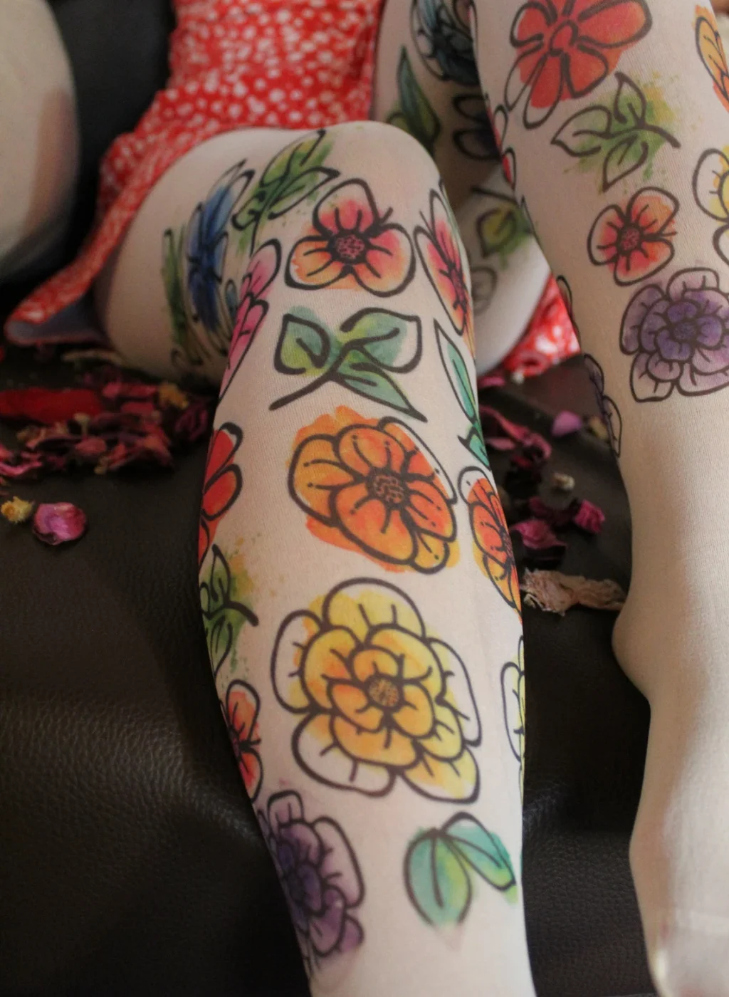 Pantimedias infantiles con estampado floral multicolor, flores grandes en tonos vivos sobre media clara mientras la niña está recostada | Kids multicolor floral print tights big vibrant flowers on light pantyhose