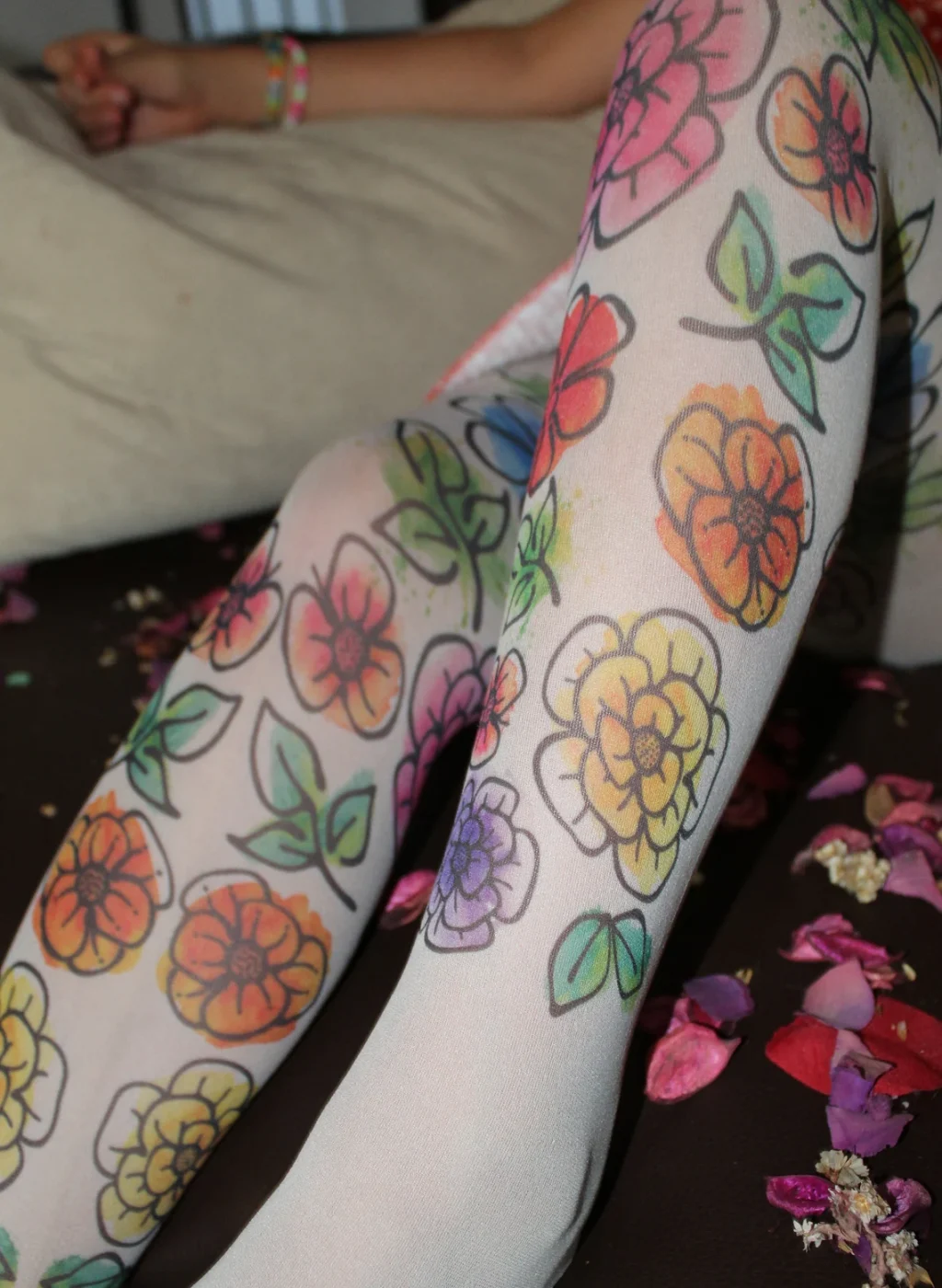 Pantimedias infantiles con flores dibujadas en tonos vivos, diseño floral sobre fondo claro con niña recostada | Kids bright floral tights hand-drawn flower pattern on light pantyhose
