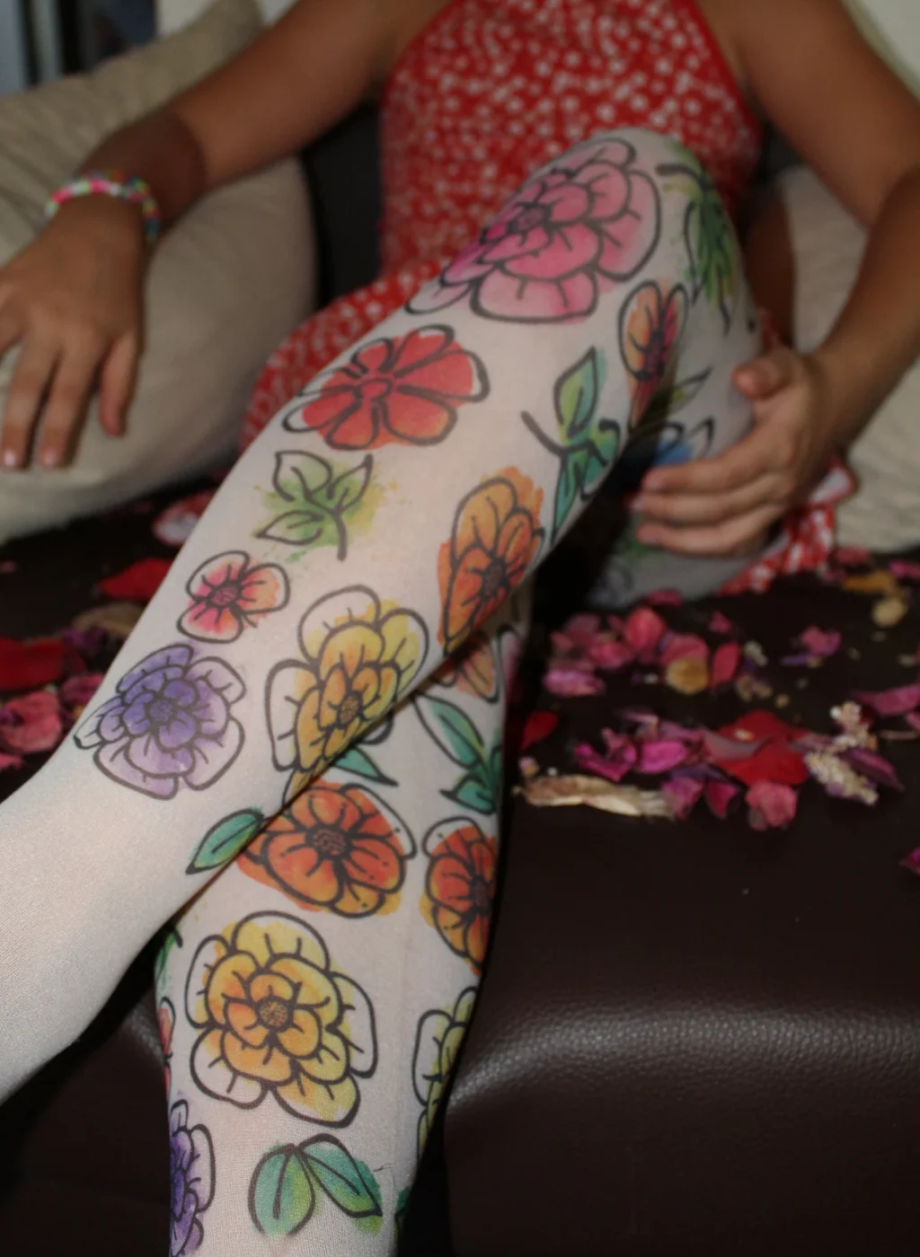Pantimedias infantiles con flores multicolor, diseño floral grande sobre media clara mientras la niña está sentada | Kids multicolor flower tights large floral pattern on light pantyhose seated